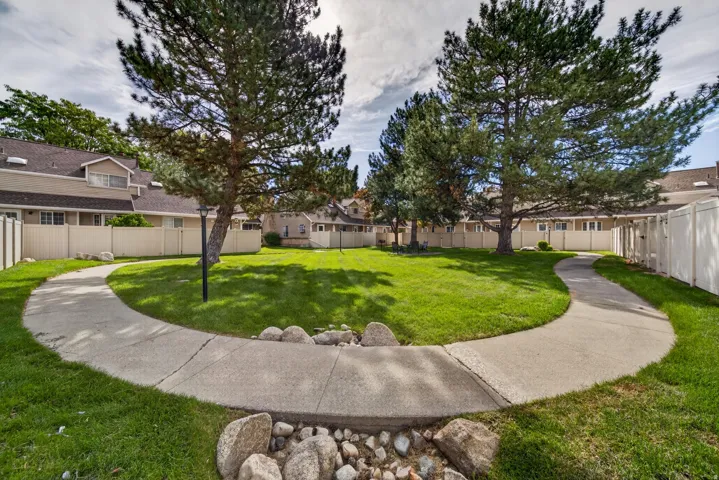 Central landscaped green space with mature trees, curved concrete pathways, and a perimeter fence