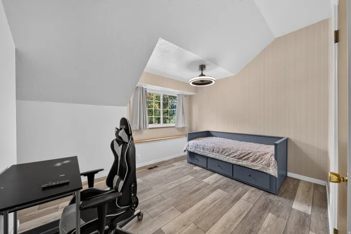 Sloped ceilings, wood-finish flooring, and a modern ceiling light fixture