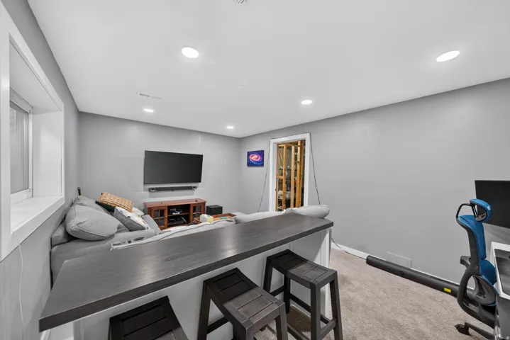 Built-in bar countertop, recessed ceiling lighting, carpet flooring, window with white trim, and a built-in media console