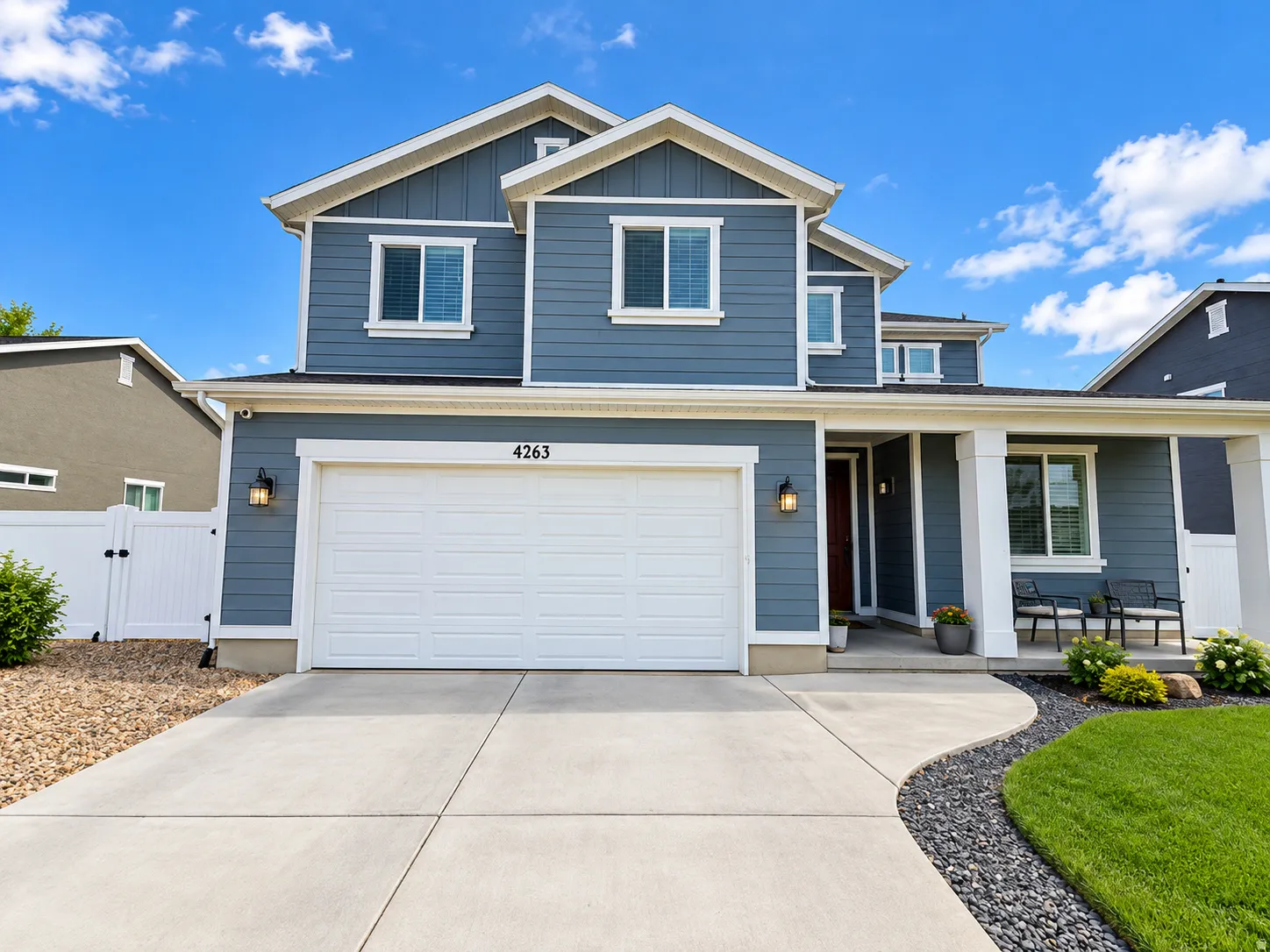 Two-story residence featuring blue siding, white trim accents, a two-car garage, and a covered porch entry