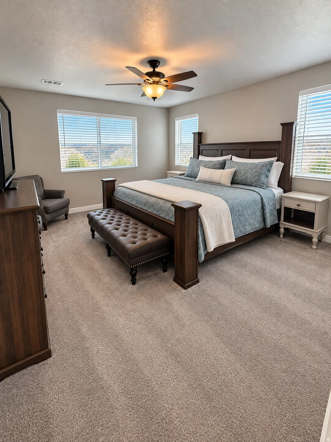 Expansive carpeted room featuring multiple windows, a ceiling fan with integrated lighting, and neutral wall tones