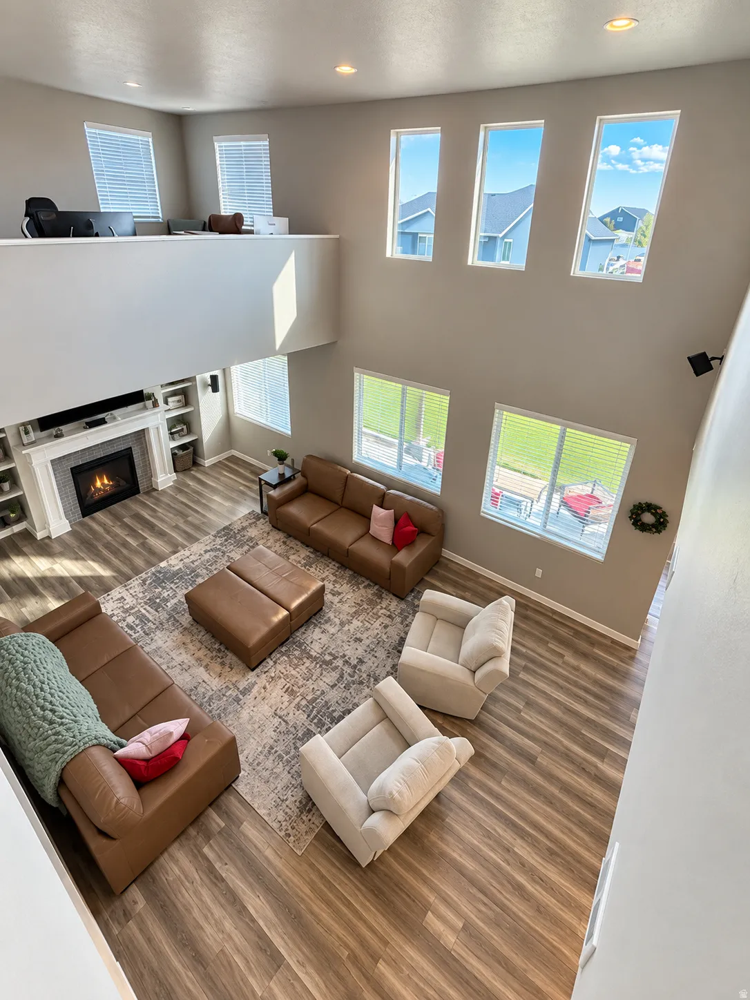 Vaulted ceiling living area featuring multiple windows, recessed lighting, a fireplace with a mantel, and wood-finish flooring