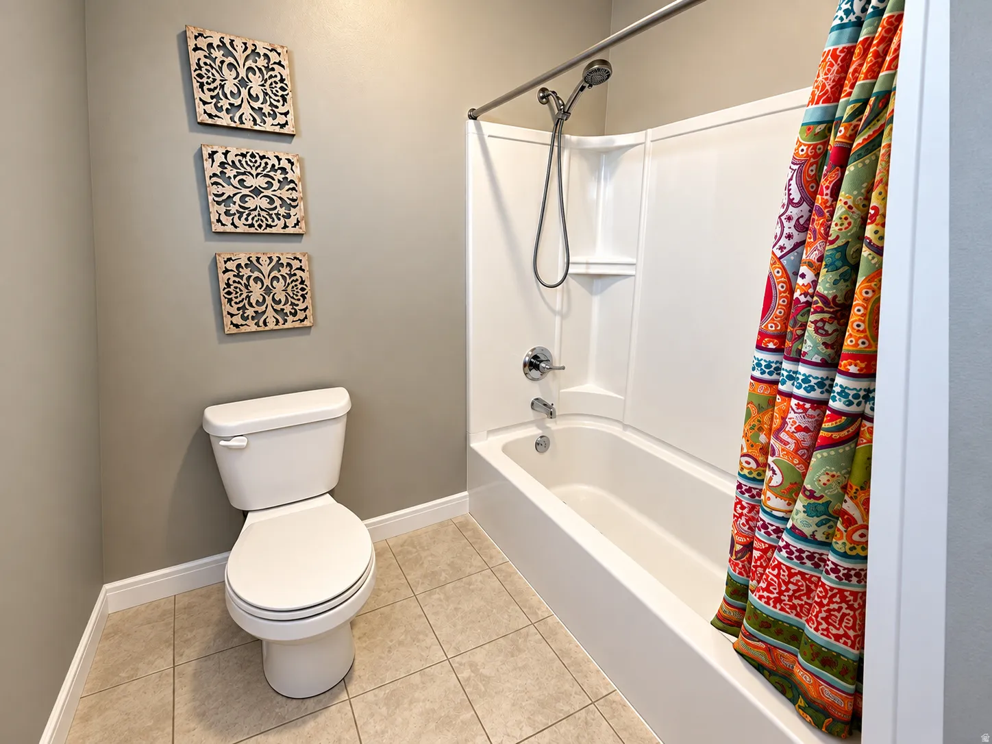 White toilet with a matching tank, a built-in shower/tub combination, and tiled flooring