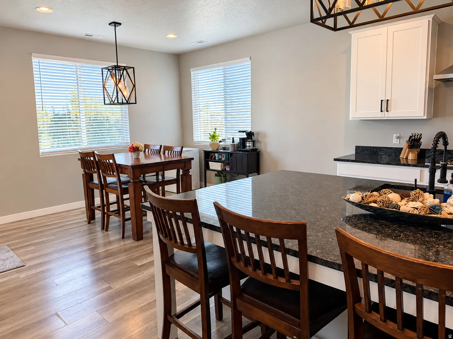 Kitchen island with dark countertop, white cabinetry with dark hardware, wood-finish flooring, and recessed lighting