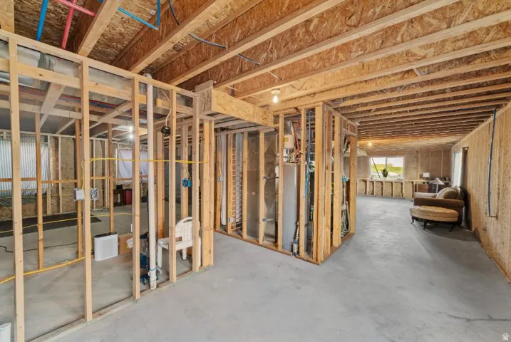 Unfinished basement space featuring exposed wood framing, concrete flooring, and visible utility infrastructure