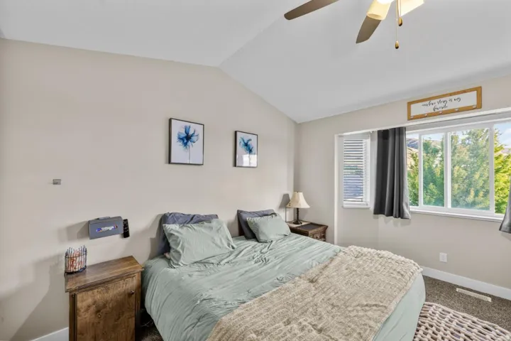 Vaulted ceiling with a ceiling fan, carpeted flooring, and a large window