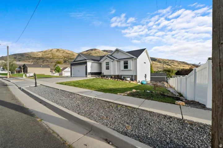 Contemporary exterior with a two-car garage, manicured lawn, and a white privacy fence