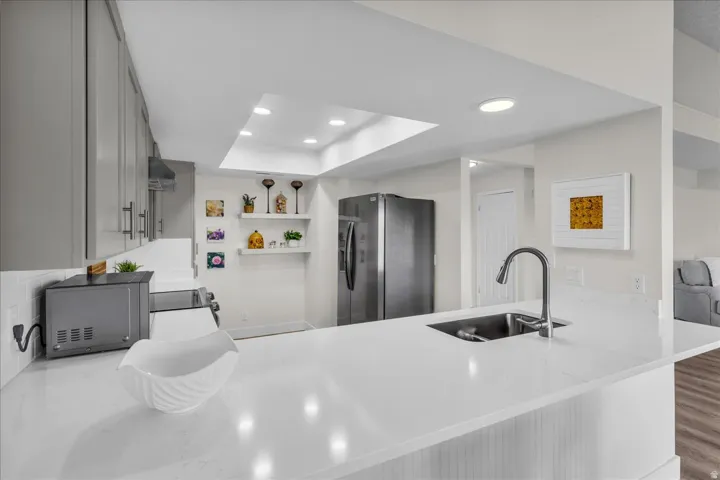 Kitchen featuring a skylight, recessed lighting, stainless steel sink with a gooseneck faucet, light-toned cabinetry, and white countertops