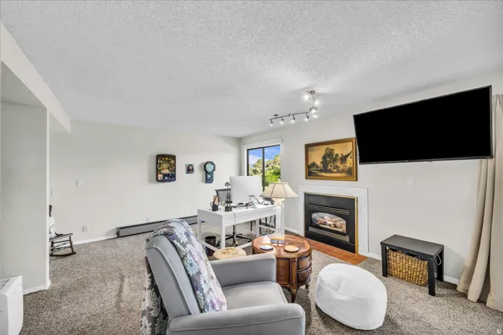 Built-in fireplace with a white surround, track lighting, and soft carpet flooring