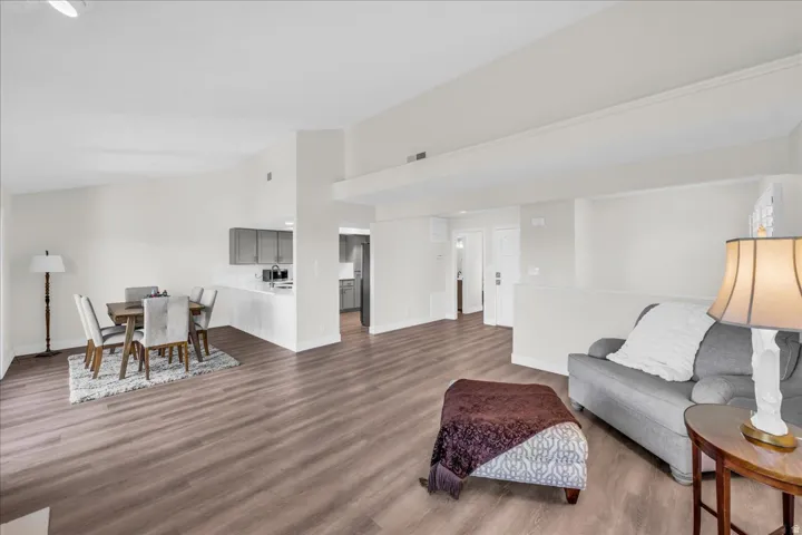 Vaulted ceilings, wood-finish flooring, white walls, and a partial wall separating spaces
