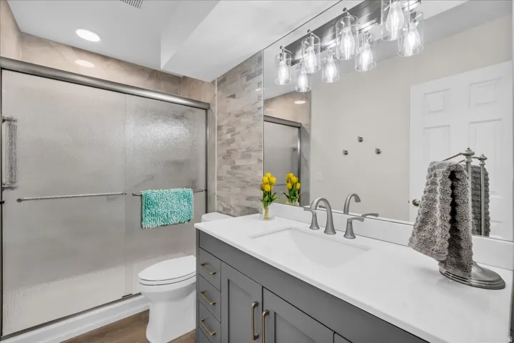 Gray vanity with gold-tone hardware, white countertop, rectangular undermount sink, and brushed nickel faucet