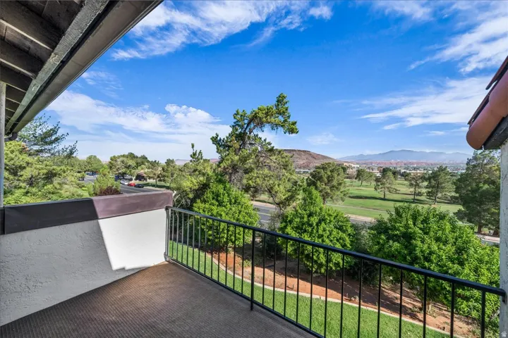 Balcony with black metal railing, offering expansive golf course and mountain scenery