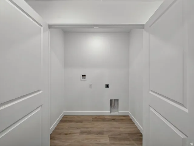 Dedicated utility space featuring wood-finish flooring, white walls, and bright overhead lighting