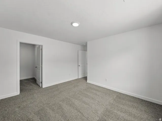 Neutral white wall paint, recessed lighting, white interior doors, and grey carpeting