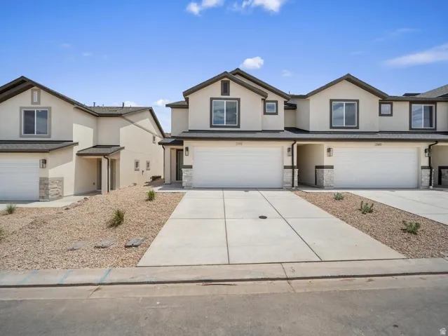 Stucco exterior with stone accents, dark trim windows, attached garages, and concrete driveways