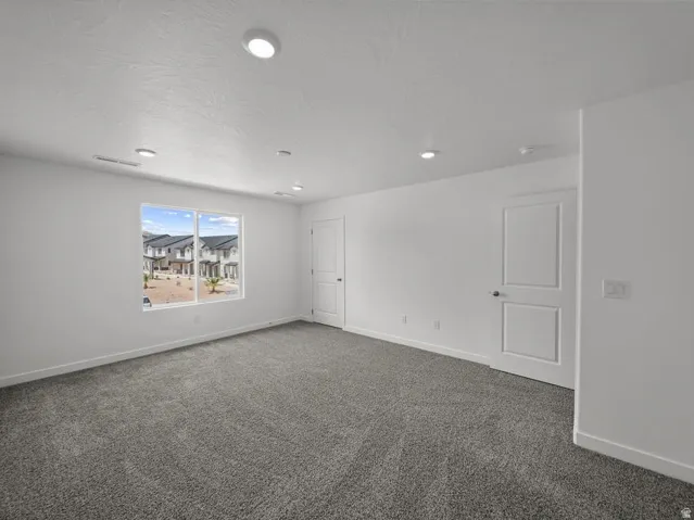 Spacious interior featuring a large window, recessed lighting, white walls, and gray carpeting