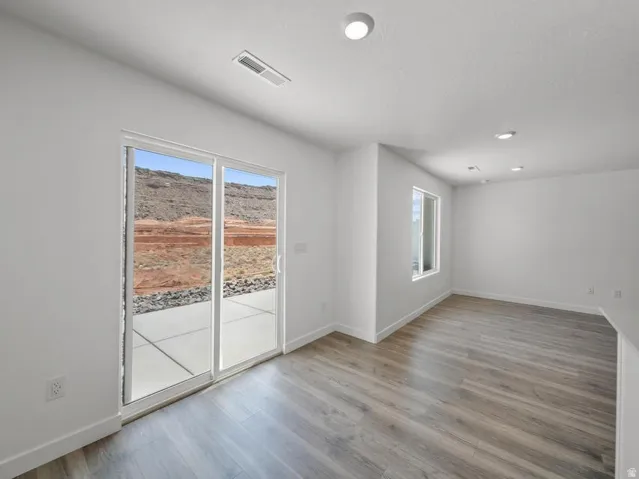 Wood-finish flooring, recessed lighting, and a sliding glass door providing access to a concrete patio
