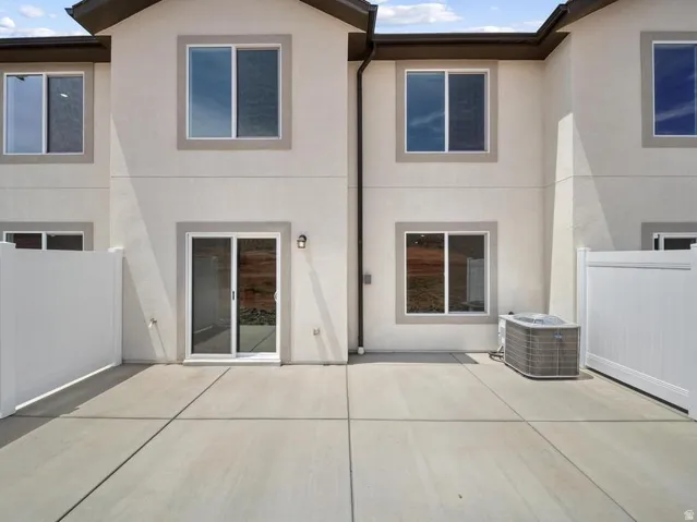 Poured concrete patio featuring privacy fencing, a sliding glass door, and exterior sconce lighting