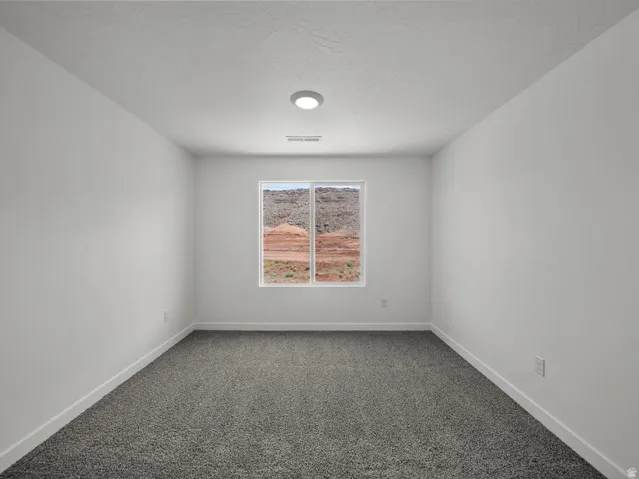 Recessed lighting, neutral paint, gray carpeting, and a window with a desert landscape