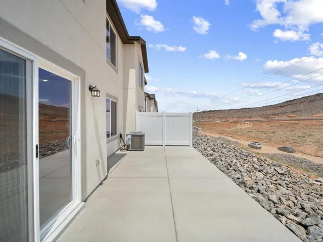 Paved patio with white vinyl fencing and exterior wall sconce
