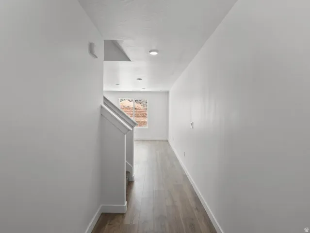 Wood-finish flooring with white baseboards, recessed lighting, and a window providing natural light