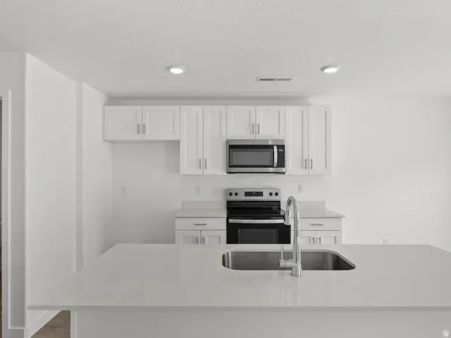 Kitchen featuring white shaker cabinetry, stainless steel appliances, recessed lighting, and light-toned countertops