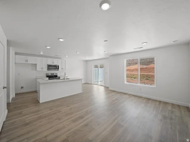 Open concept design with wood-finish flooring, recessed lighting, and white cabinetry