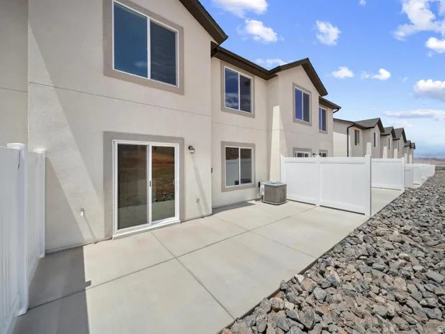 Concrete patio with a white privacy fence, featuring a sliding glass door and an exterior light fixture