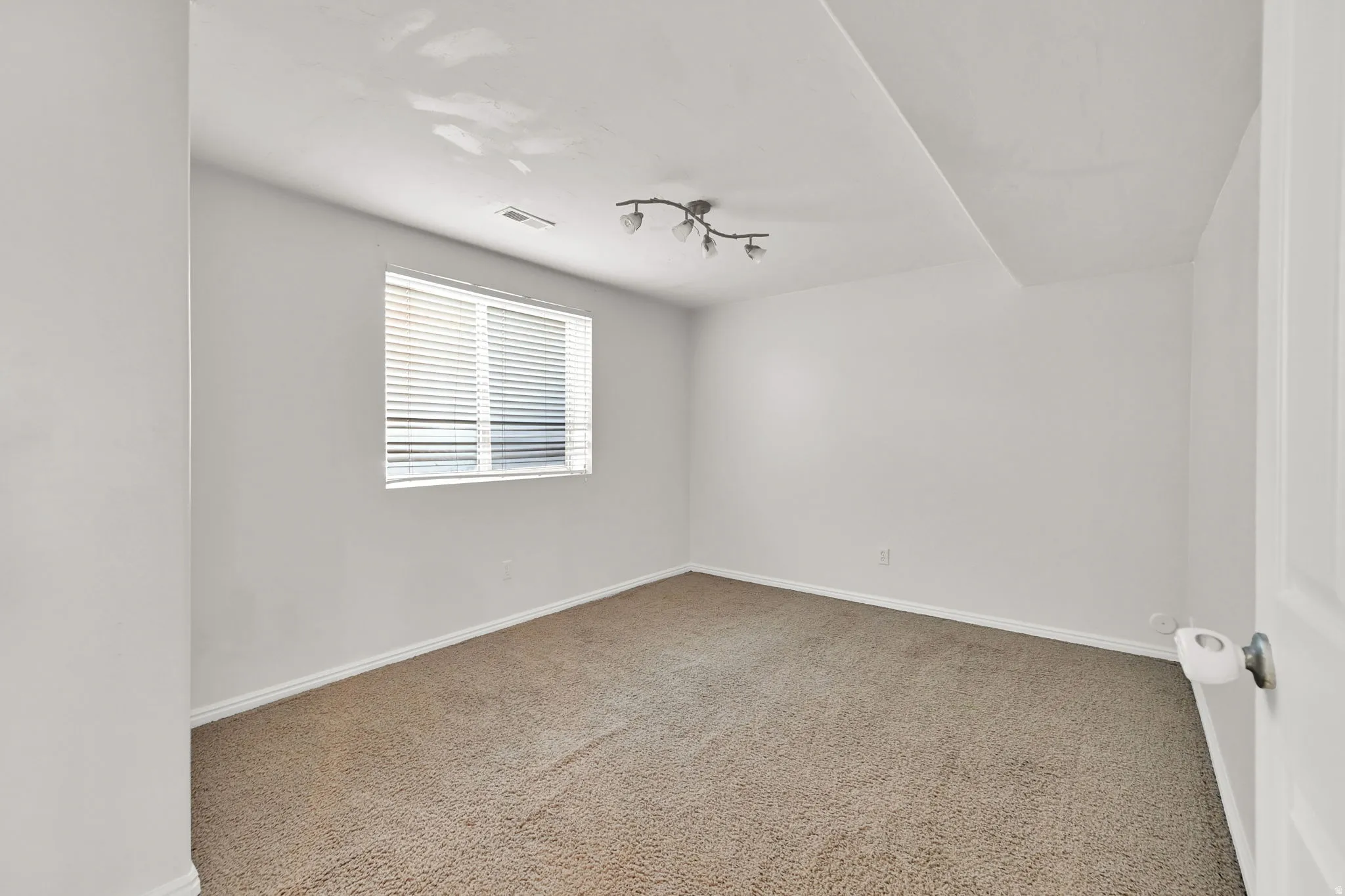 Recessed window with horizontal blinds, neutral wall paint, and textured carpet flooring