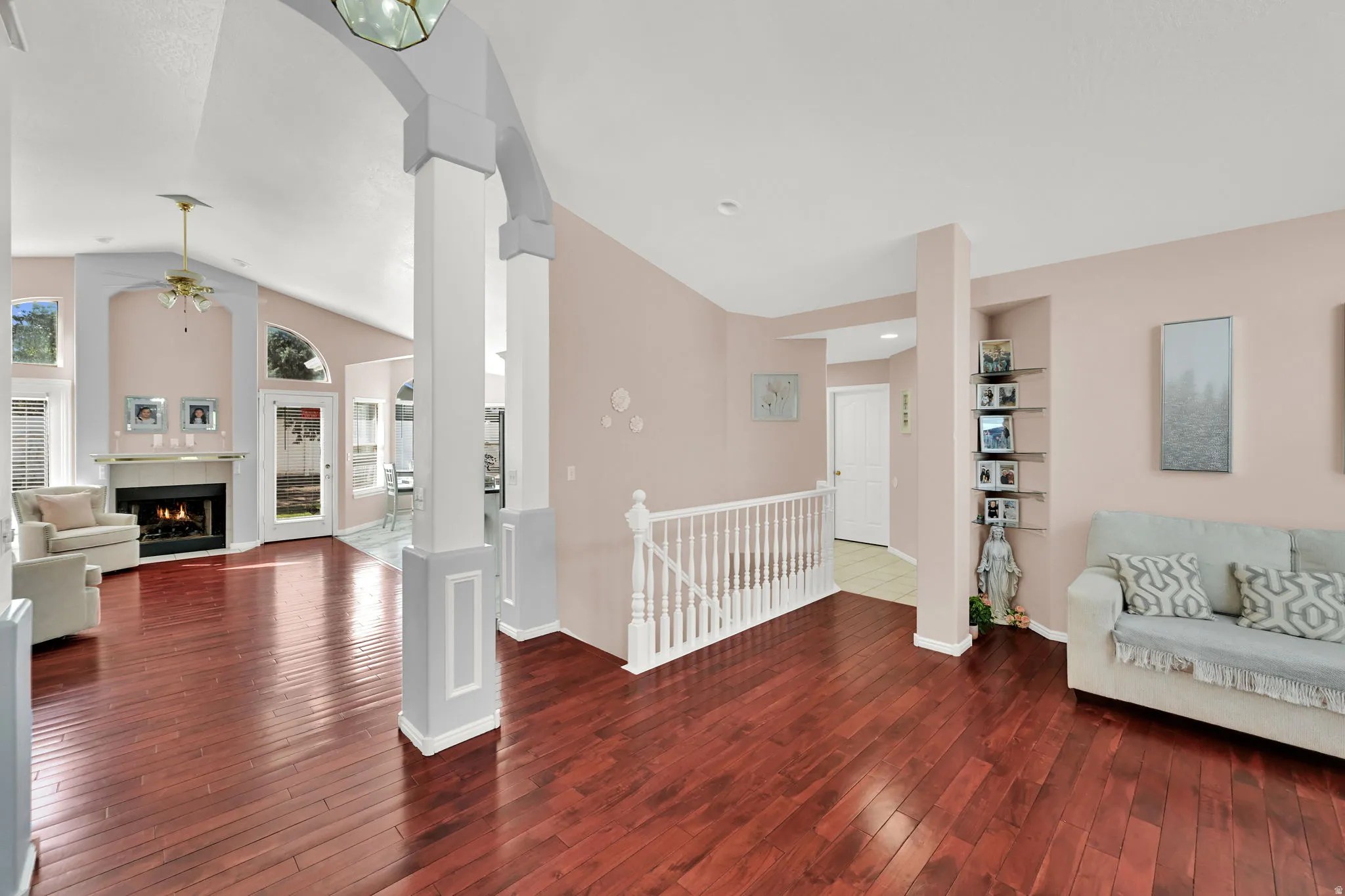 Wood-finish flooring throughout, vaulted ceiling, arched doorway, fireplace with mantel, and built-in shelving