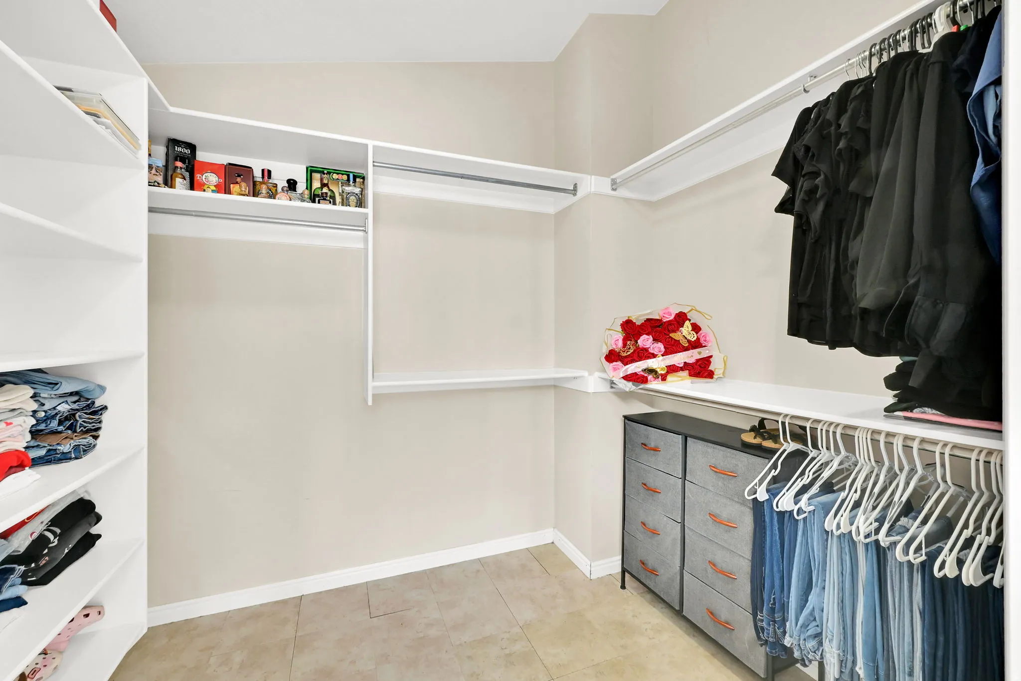 Walk-in closet featuring built-in shelving, multiple hanging rods, and neutral-toned wall paint