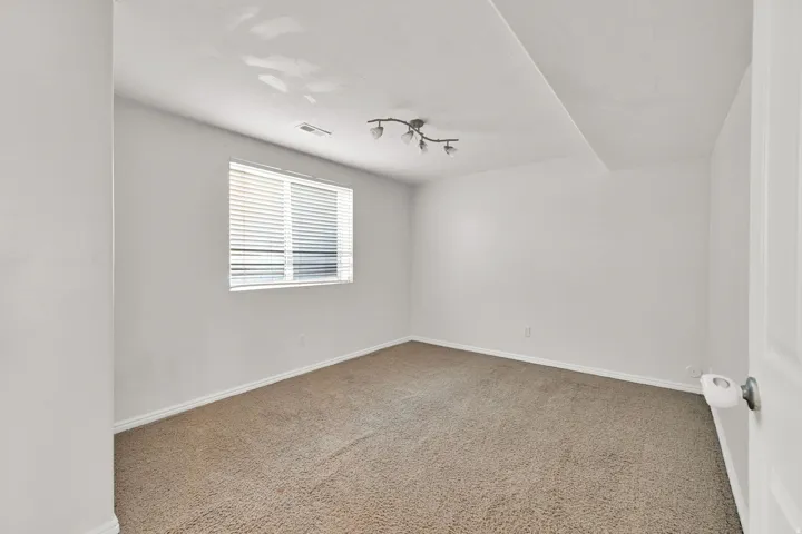 Recessed window with horizontal blinds, neutral wall paint, and textured carpet flooring