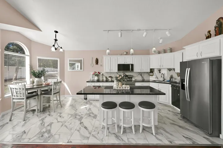 Kitchen featuring white cabinetry, a central island with countertop seating, stainless steel appliances, and a marble-finish tile floor