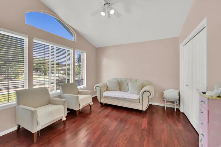 Vaulted ceiling with an arched transom window, wood-finish flooring, and a ceiling fan with integrated lighting