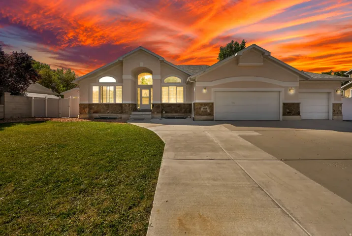 Stucco exterior with stone accent, arched entry, multiple garage bays, and a concrete driveway