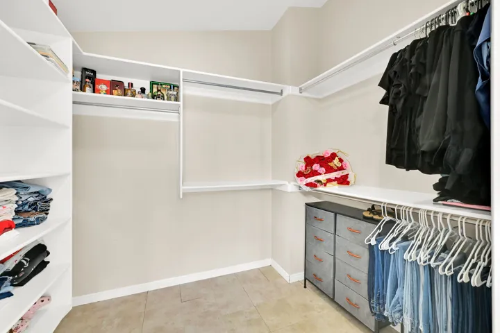 Walk-in closet featuring built-in shelving, multiple hanging rods, and neutral-toned wall paint