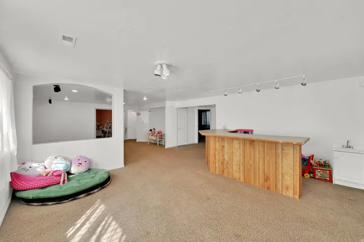 Spacious recreational area featuring recessed lighting, track lighting, and a built-in wood-finish bar with a countertop