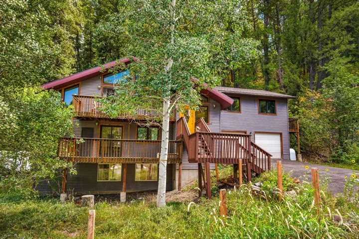 Multi-level property with a red sloped roof and gray siding