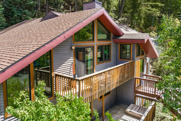 Multi-level deck with wooden railings, expansive windows, and a shingle roof