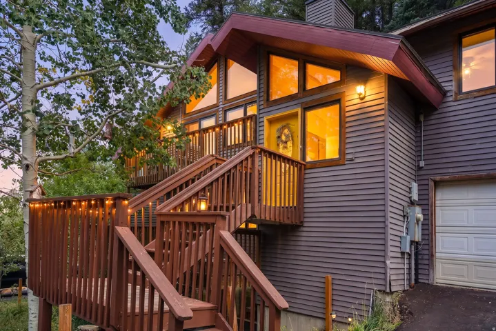 Multi-level exterior deck with wood railings, expansive windows, a prominent garage, and horizontal siding