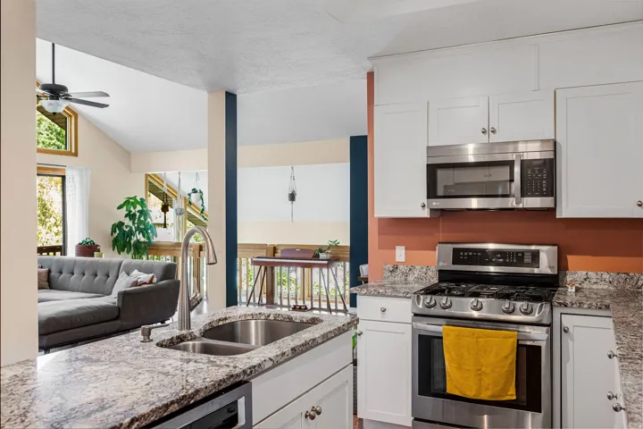 Kitchen featuring white shaker-style cabinetry, stainless steel appliances, and a double basin sink with a gooseneck faucet