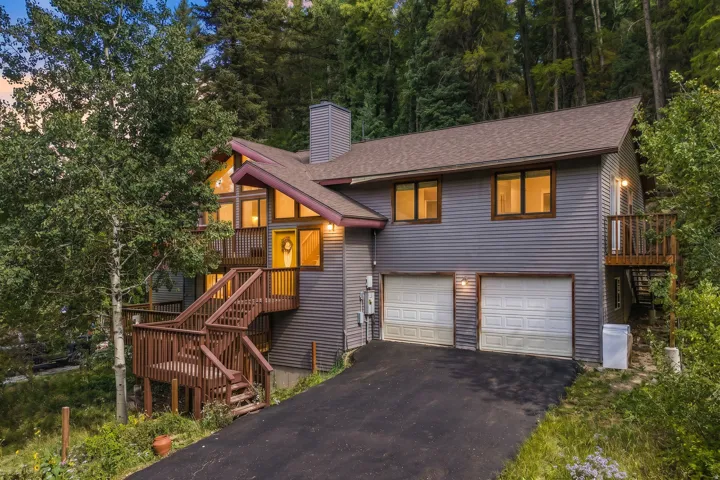 Multi-level residence featuring a two-car garage, multiple decks, and extensive windowing