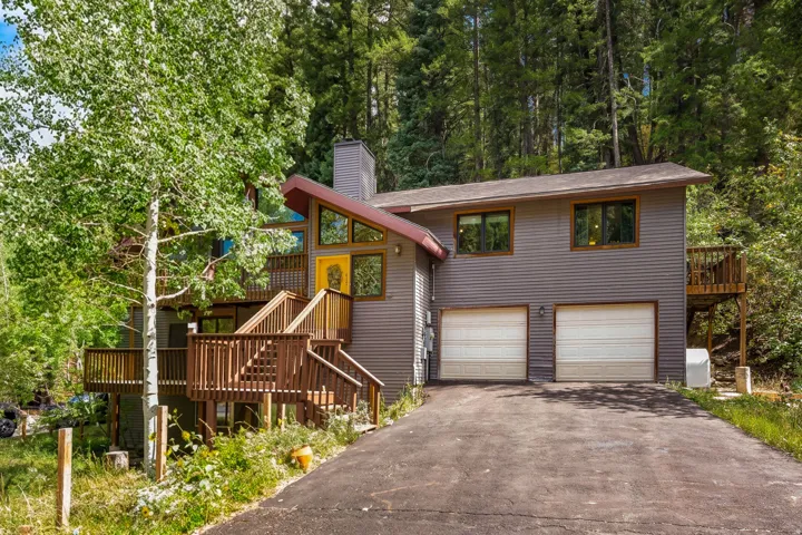 Contemporary exterior with a two-car garage, multiple wood decks, and an asphalt driveway