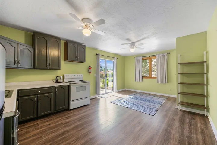 Kitchenette with dark-finished cabinetry, light countertops, and a white electric range