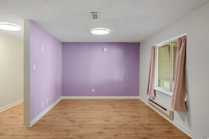 Wood-finish flooring, white trim, recessed lighting, and a prominent window