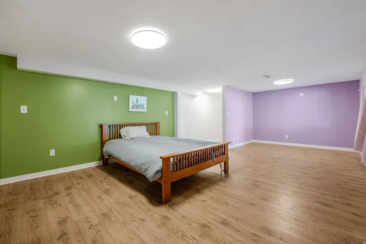 Lower level bedroom. Wood-finish flooring, recessed ceiling lighting, and distinct wall colors