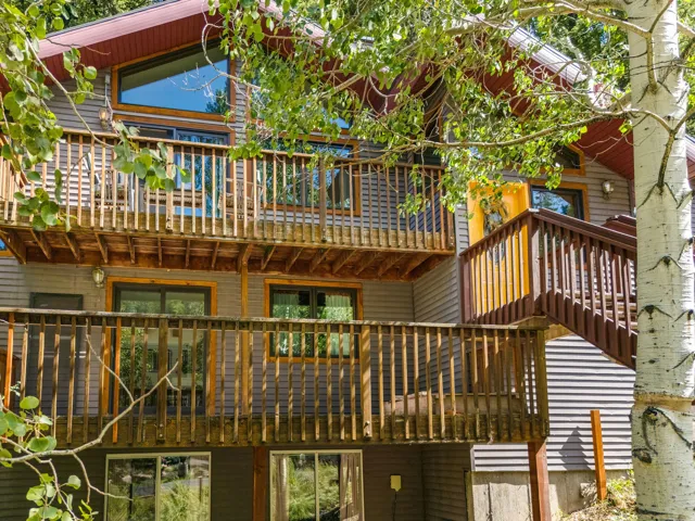 Multi-level dwelling with wood siding, multiple wood decks, exterior stairs, and extensive fenestration