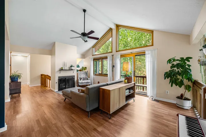 Vaulted ceiling, wood-finish flooring, fireplace with hearth, and floor-to-ceiling windows