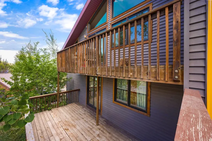 Multi-level deck with wood railing, large windows, and an angled roofline