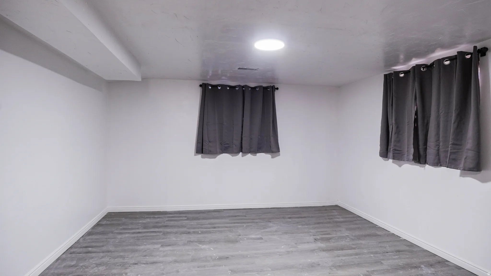 White walls with a single recessed ceiling light and wood-finish flooring